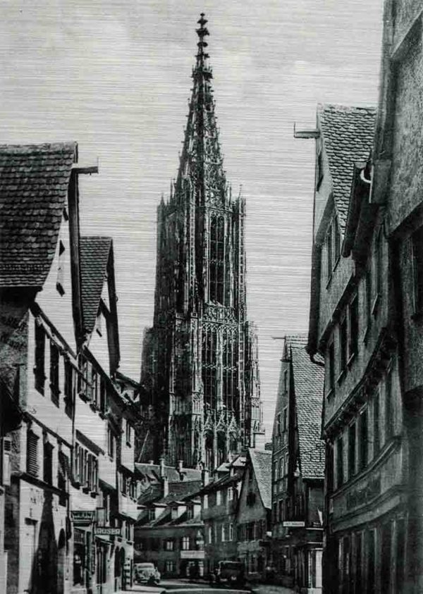 Ulmer Münster. Das Bild zeigt eine historische Aufnahme aus der Walfischgasse in Ulm mit Blick auf den Turm des Ulmer Münsters. Auf der Straße stehen Autos und an beiden Straßenseiten sind die Giebel der Stadthäuser zu sehen.